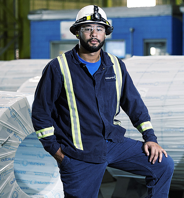 person working in mill standing in front of stainless steel coil